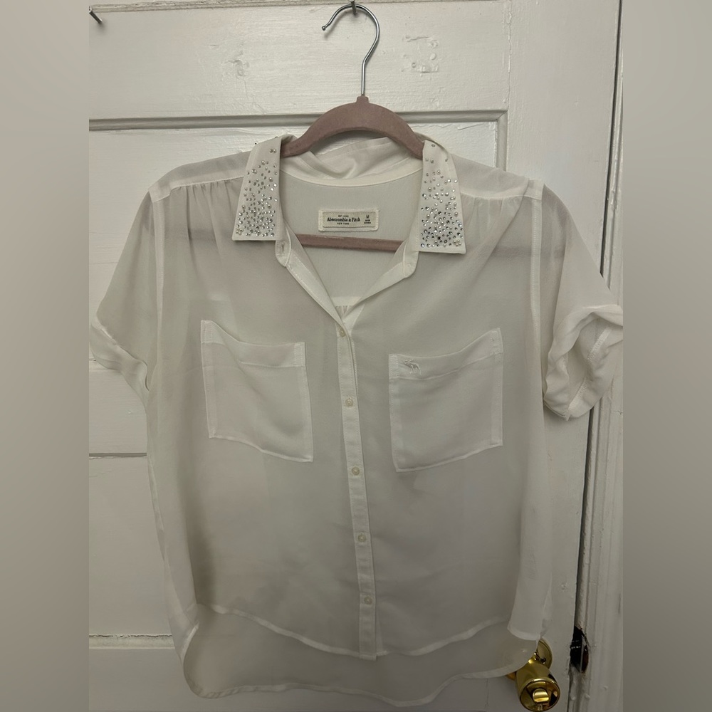 Sheer white short sleeve button up with pearl and stone appliqués.